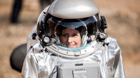 You see the face of analog astronaut Dr. Carmen Köhler in her silver shining space suit, smiling behind her helmet visor.
